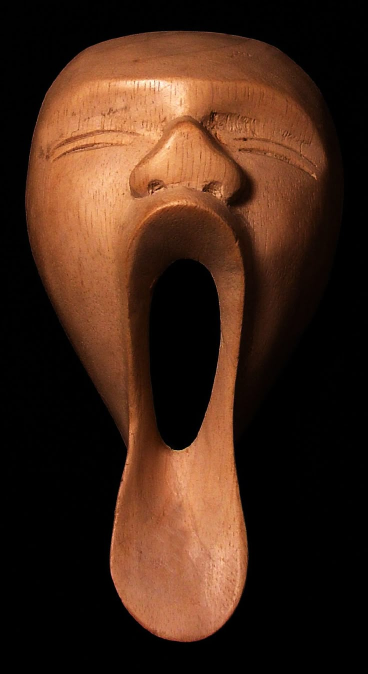 a wooden sculpture with an open mouth on a black background