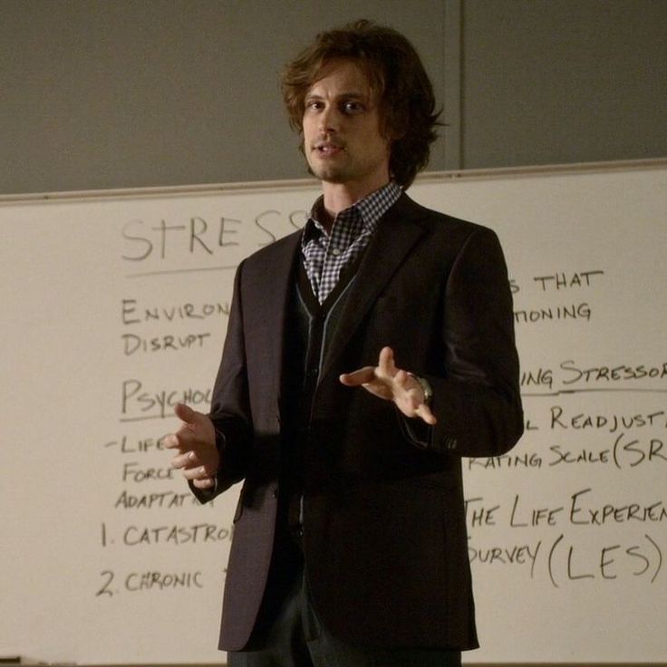 a man standing in front of a whiteboard with writing on the wall behind him