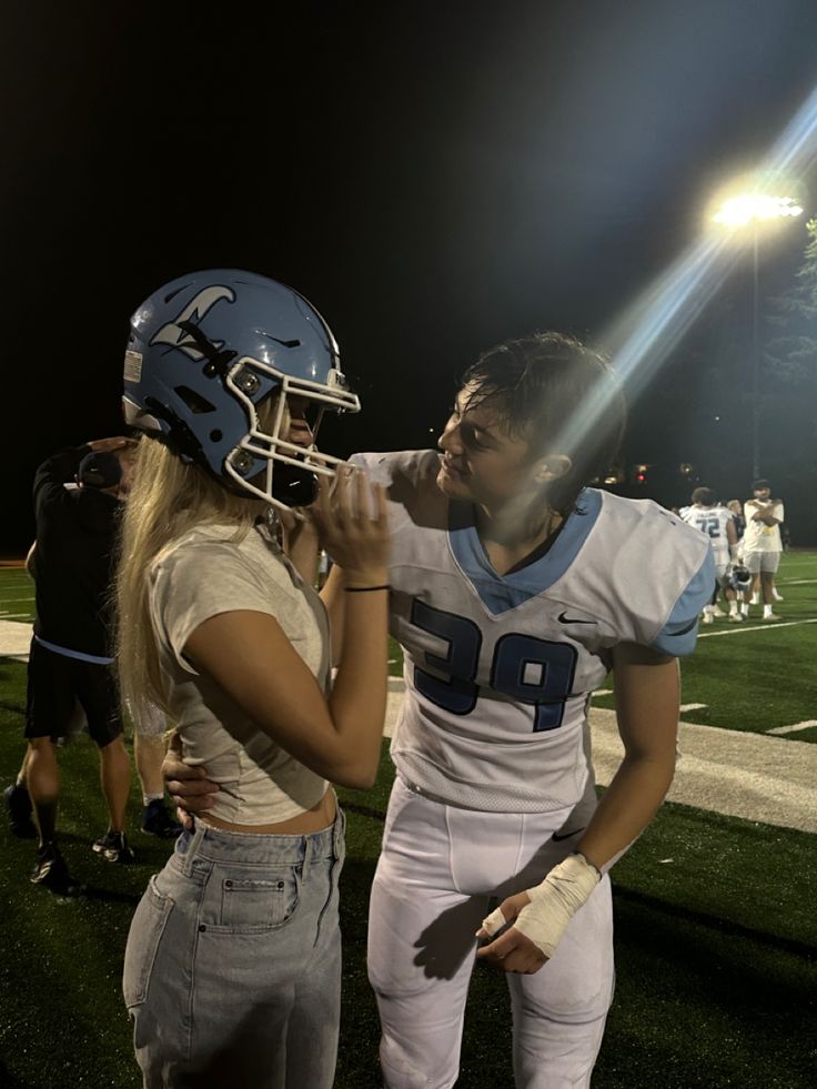 a man and woman standing next to each other on top of a field at night