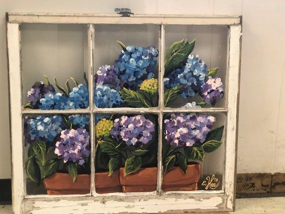 an old window with potted flowers painted on the side and in front of it