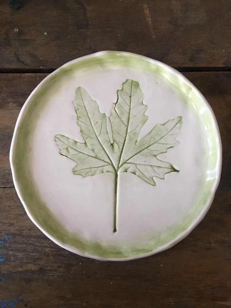 a green and white plate with a leaf on it