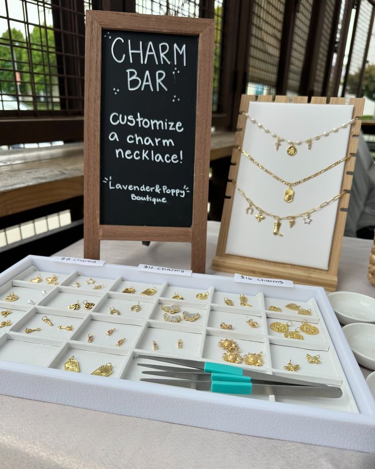 Our charm bar allows for the most beautiful custom pieces to add to your jewelry collection! Have you made one yet? #lavenderandpoppy #smallbusiness #boutique #boutiqueowner #onlineshopping #onlineboutique #outfit #clothing #clothes #shopping #charmbar #charmnecklace #charms #custom Market Table Set Up Jewelry, Permanent Jewelry Pop Up Booth, Pop Up Booth Display Ideas Jewelry, Jewelry Bar Display, Jewelry Booth Set Up, Charm Display Ideas, Bracelet Station Party, Craft Boutique, Boutique Products Ideas