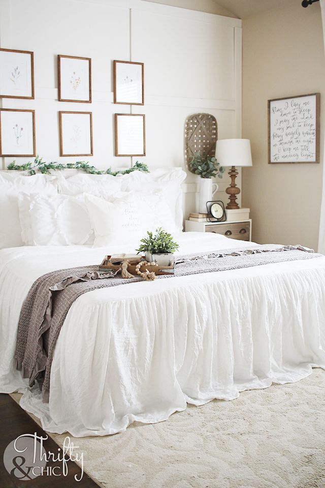 a white bed sitting in a bedroom next to pictures on the wall