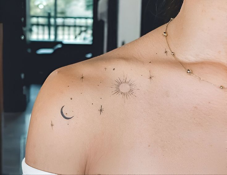 the back of a woman's shoulder with small stars and a sun tattoo on it