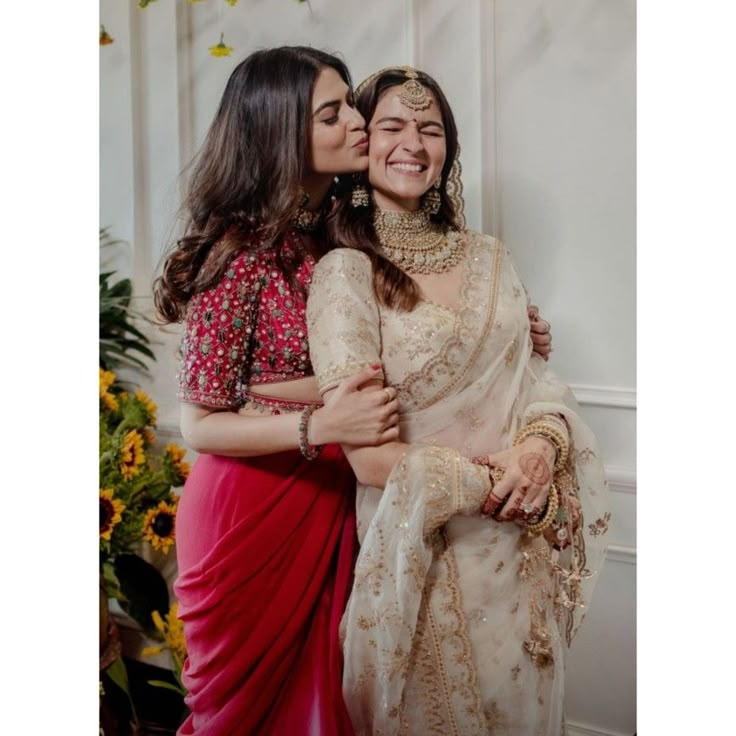 two women hugging each other in front of flowers