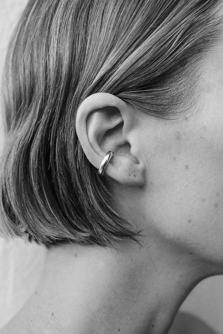 black and white photograph of a woman's ear with the top part of her nose pierced