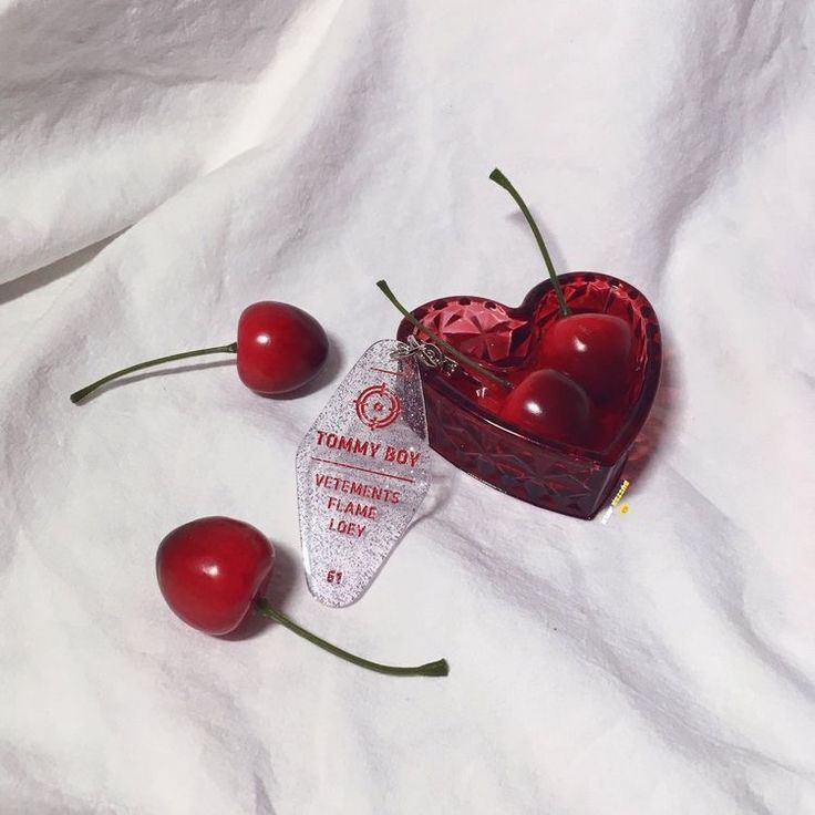 two cherries in a heart shaped box on a white sheet with the label tommy's boy