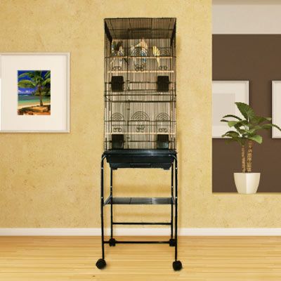 a bird cage sitting on top of a wooden floor next to a potted plant