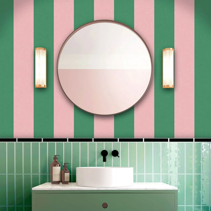 a bathroom with green and pink stripes on the wall next to a white sink under a round mirror