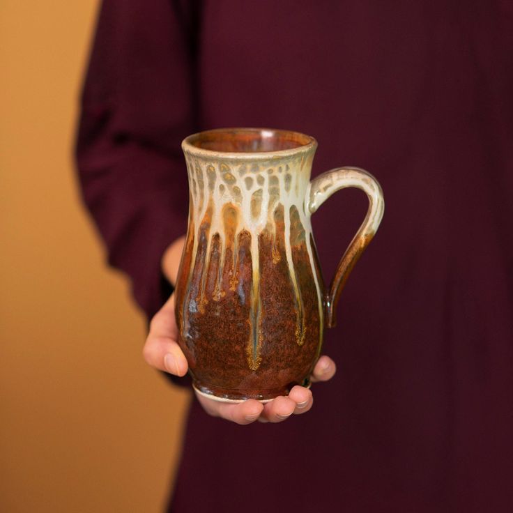 a person holding a brown and white coffee mug