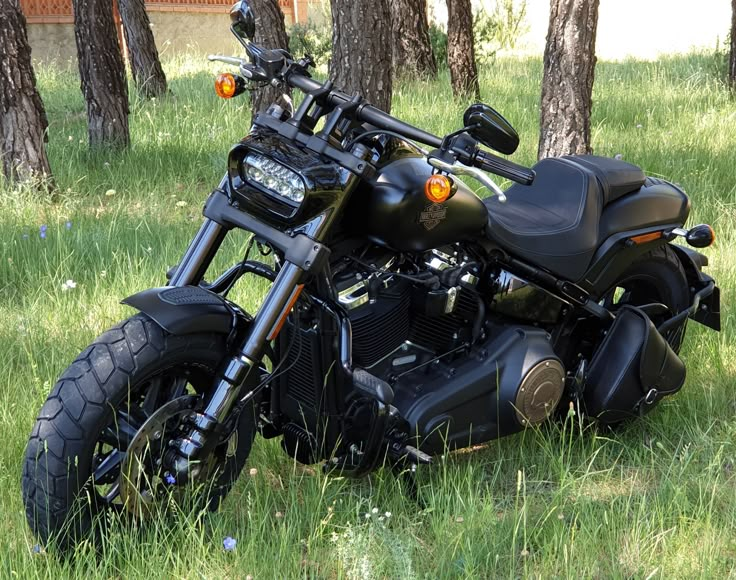 a motorcycle parked in the grass near some trees