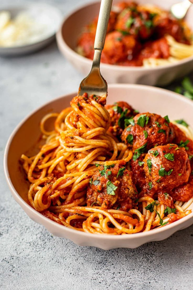 two bowls filled with spaghetti and meatballs