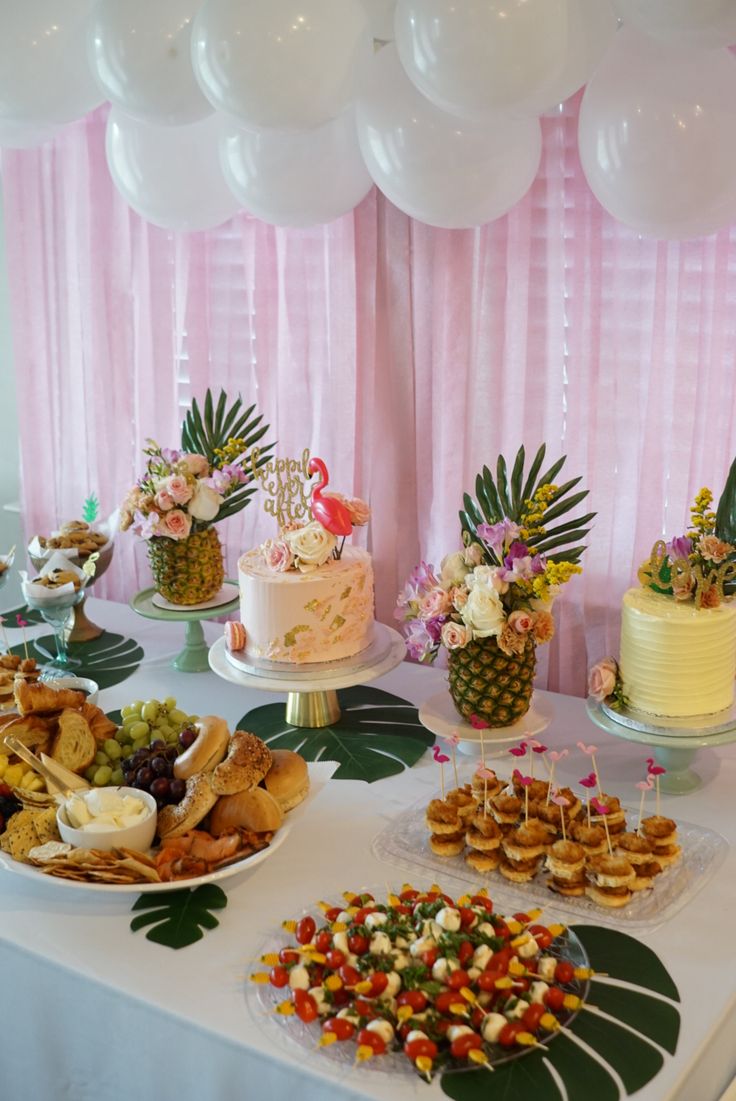 a table topped with lots of different types of food and desserts next to balloons