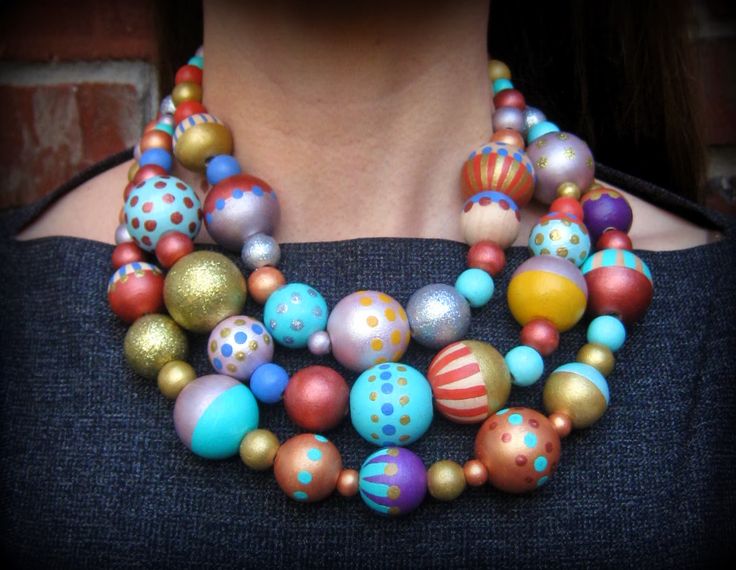 a woman wearing a multicolored necklace with polka dots and balls on it's neck