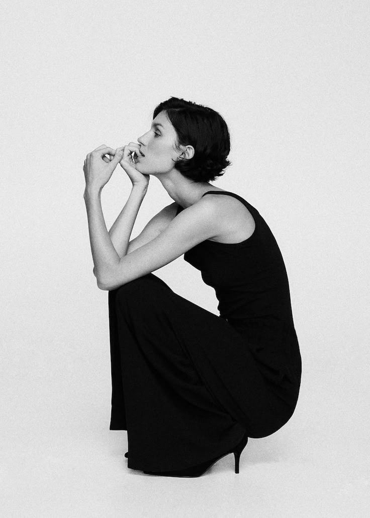 black and white photograph of a woman sitting on the floor with her hands in her mouth