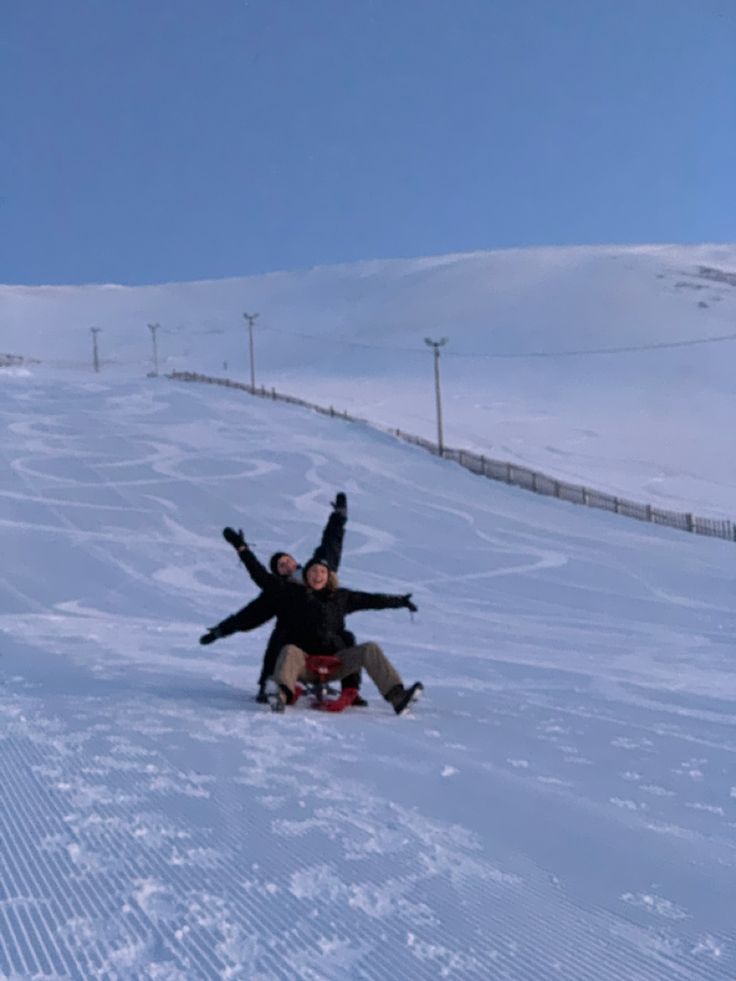 two people in the snow with their arms out and one person laying on his back