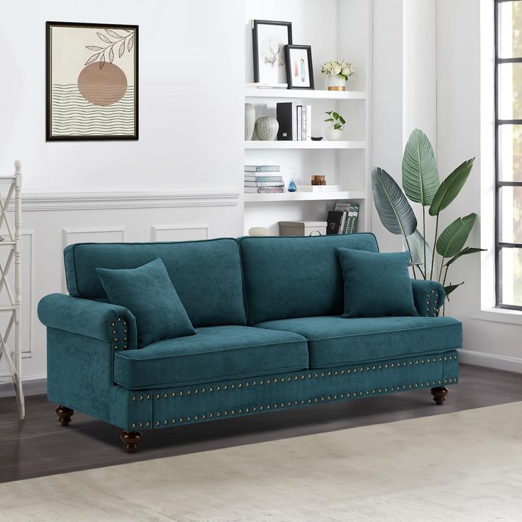 a living room scene with focus on the blue couch and bookshelf in the background