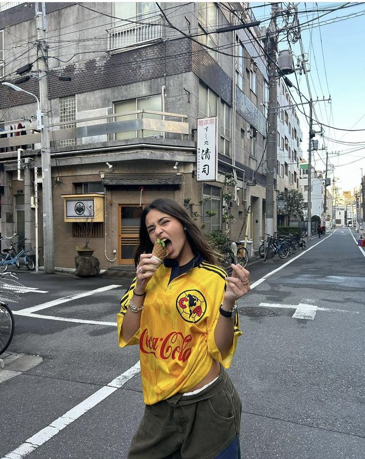 a woman standing in the middle of an empty street eating something out of her mouth