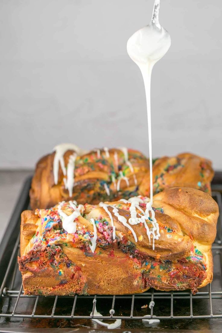 a person drizzling icing on top of a loaf of bread with sprinkles