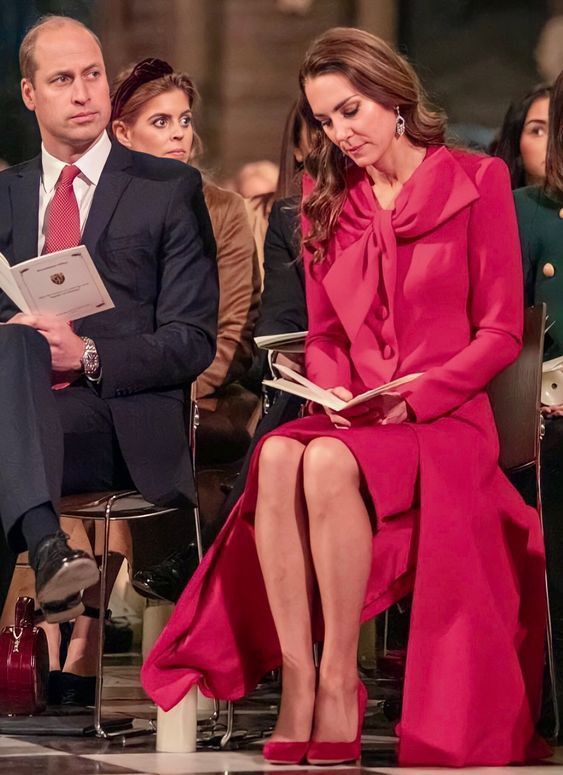 a woman in a red dress sitting next to a man wearing a suit and tie