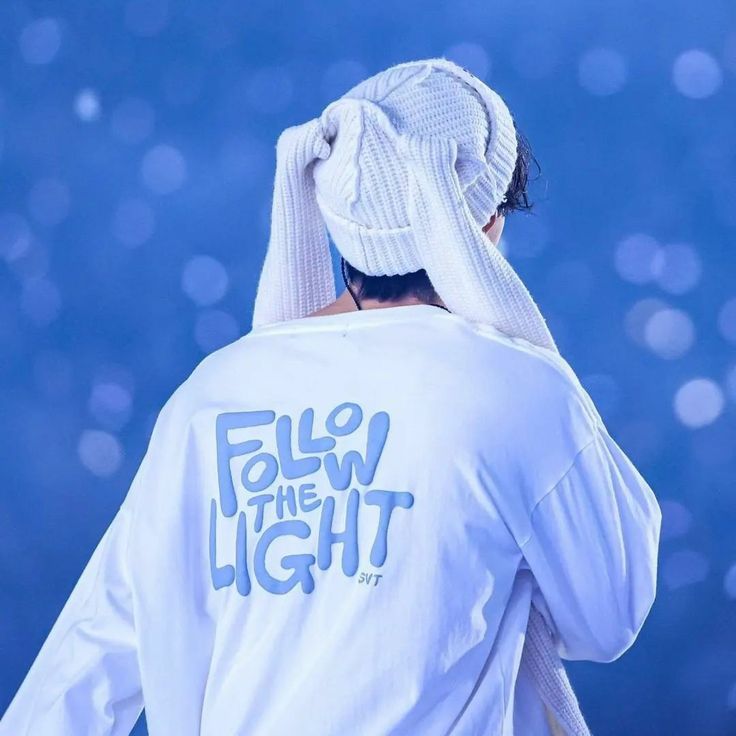 the back of a person wearing a white t - shirt that says follow the light