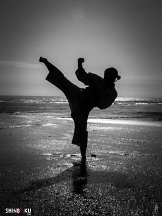 a person doing a handstand on the beach in front of the ocean at sunset