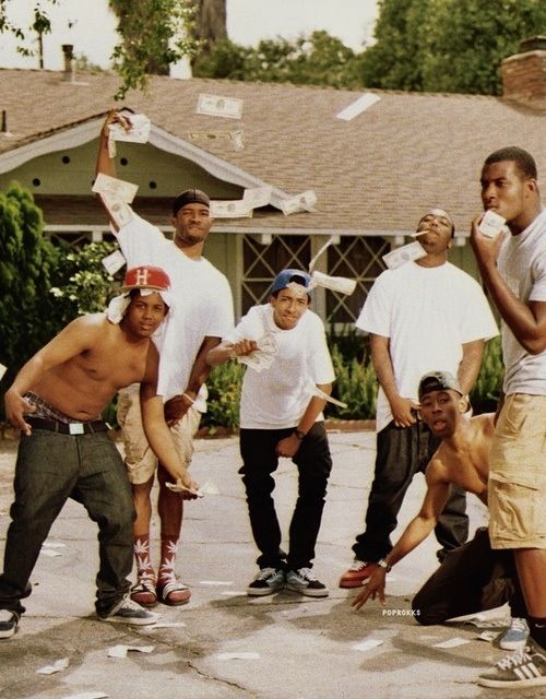 a group of young men standing next to each other in front of a house holding skateboards