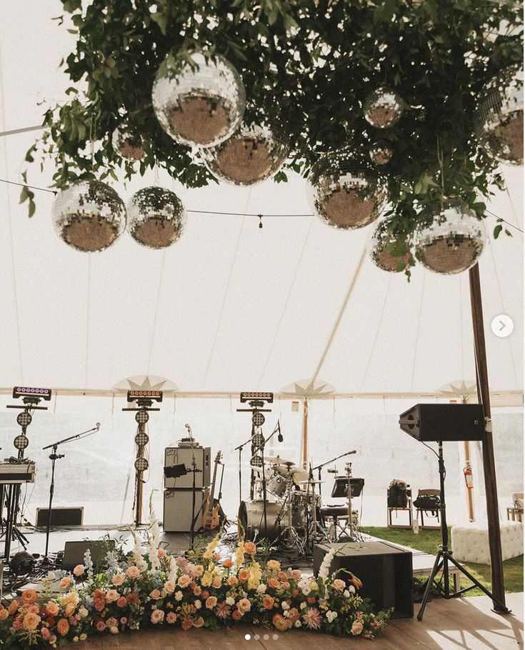 an outdoor concert venue with flowers and lights on the ceiling, as well as musical instruments