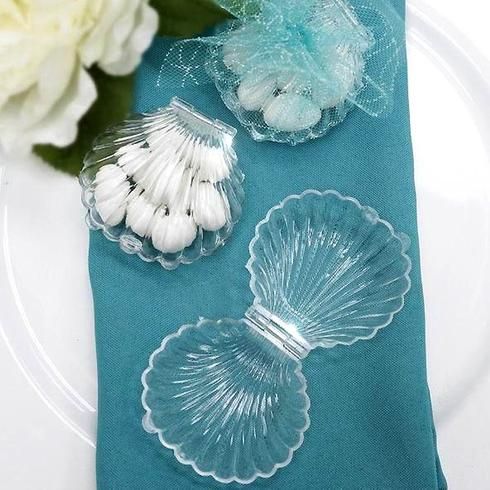 three seashells sitting on top of a blue napkin next to a white flower