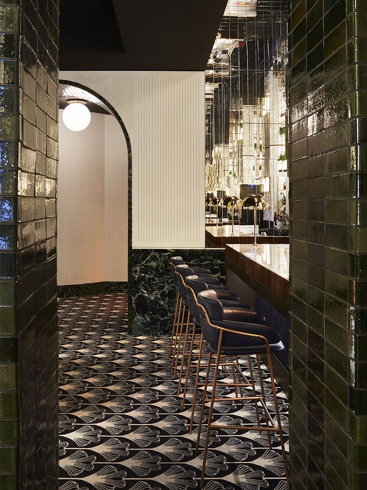 the bar is decorated with black and white tile, along with gold barstools