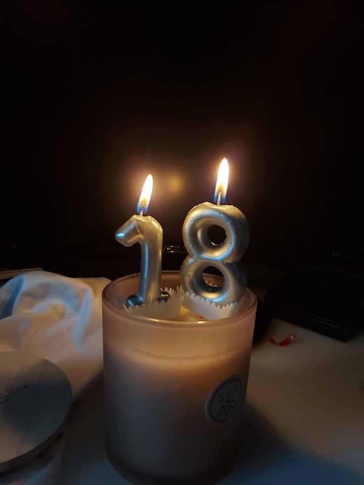 a birthday candle with the number eighteen on it and two lit candles in the middle