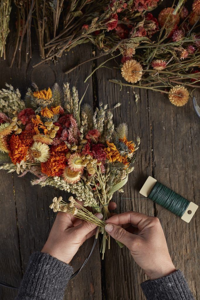 someone is arranging flowers on a wooden table with scissors and spools of thread