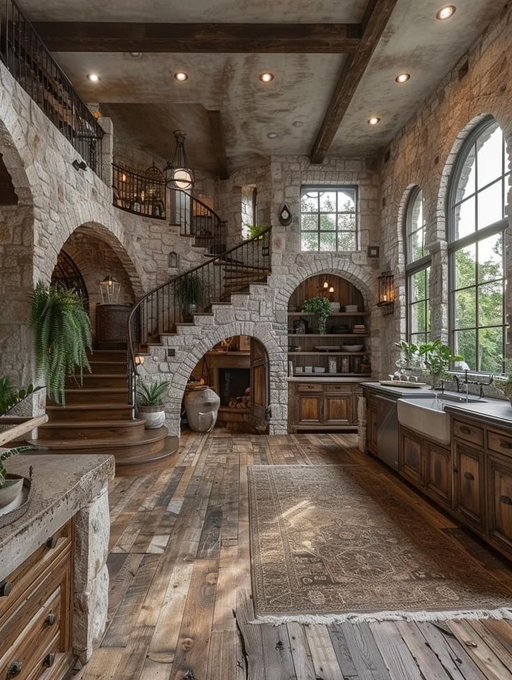 a large kitchen with stone walls and wooden floors, along with an arched doorway leading to the second floor