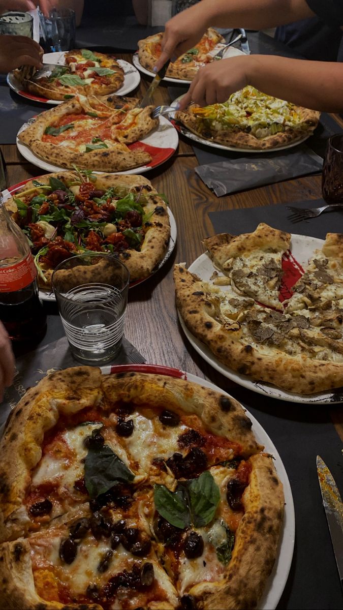 a table full of pizzas with people eating them