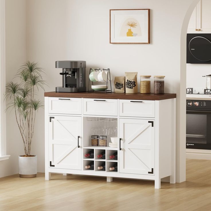 a kitchen with white cabinets and wooden counter top next to a potted palm tree