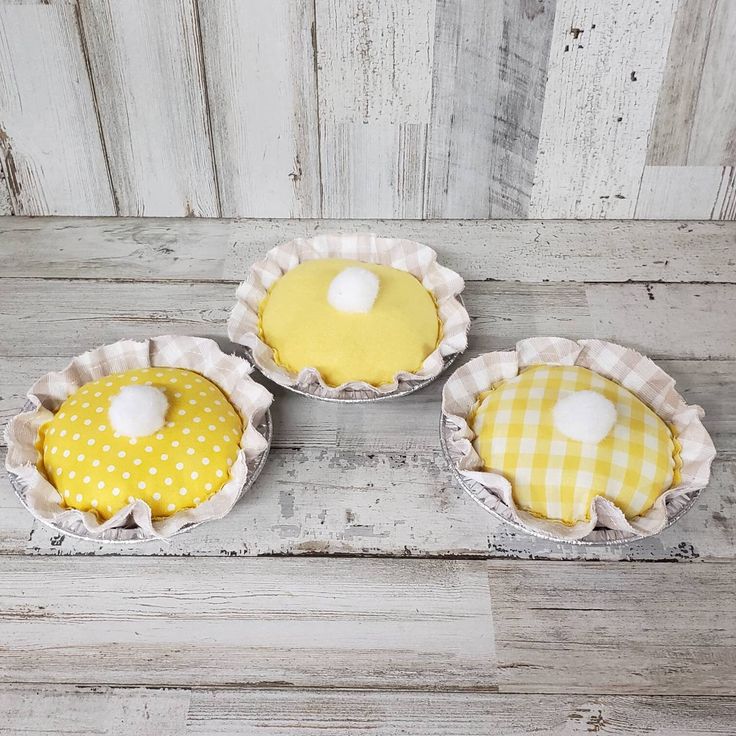 three yellow and white pies sitting on top of a wooden table