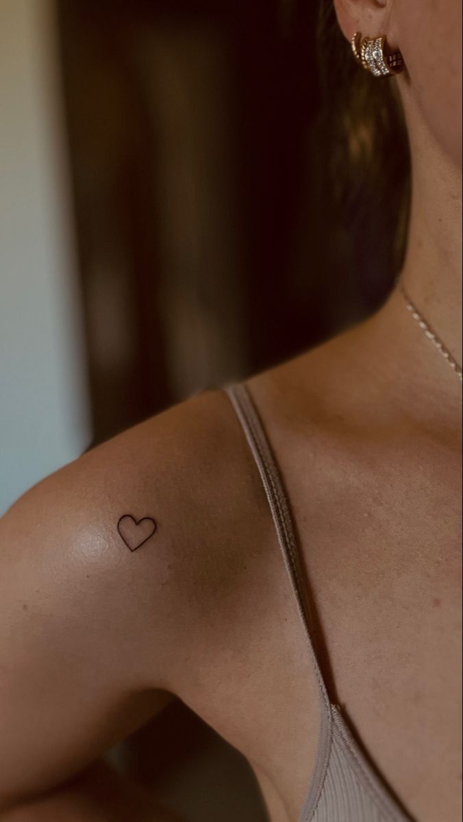 a woman with a small heart tattoo on her left arm and right arm behind her shoulder