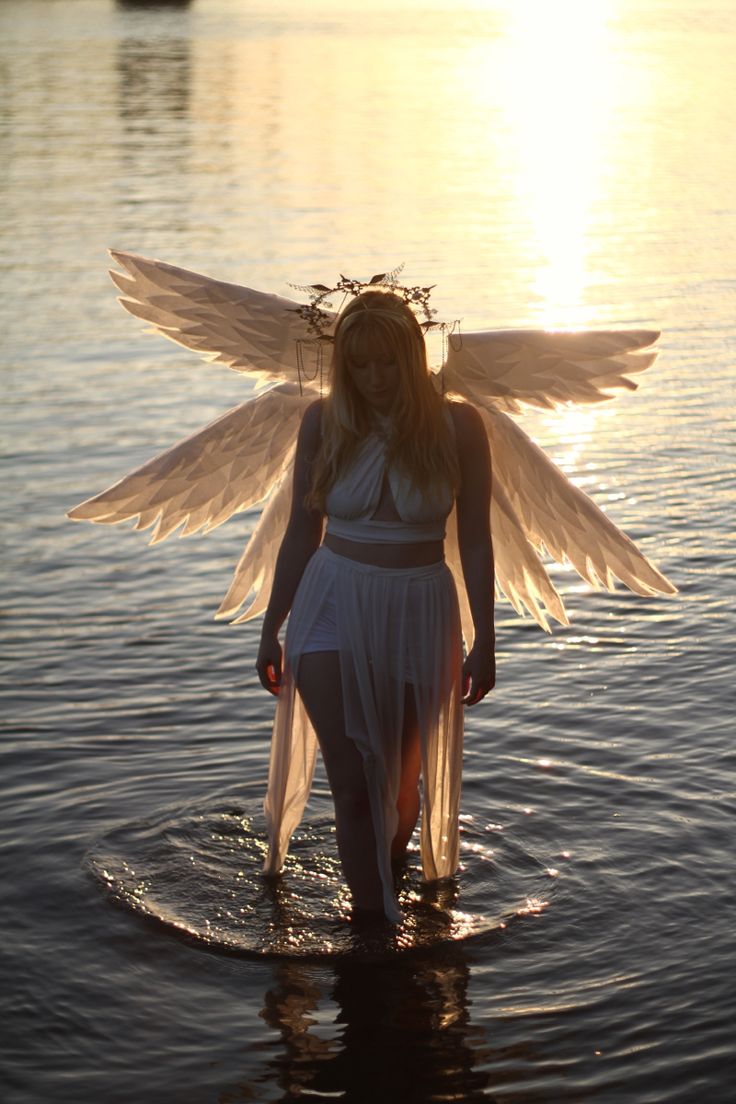 a woman with angel wings standing in the water