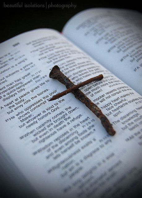 an open book with a rusty cross on it's cover and the pages are white