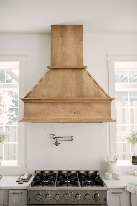 a stove top oven sitting inside of a kitchen next to a wall mounted range hood