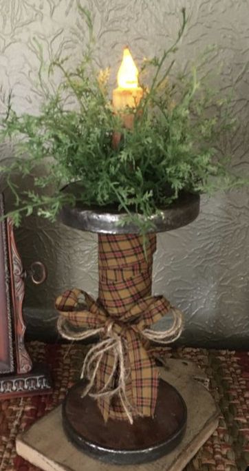 a vase filled with green plants on top of a table next to a book and candle