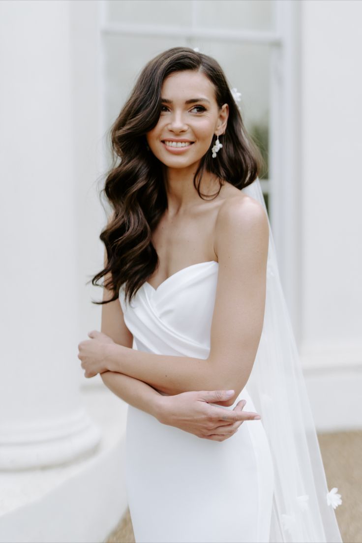 a woman in a white dress is posing for a photo with her arms folded out