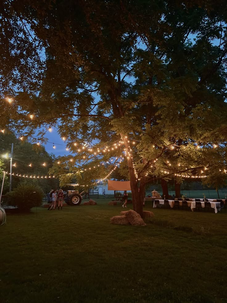 an outdoor dining area is lit up at night with string lights strung across the trees