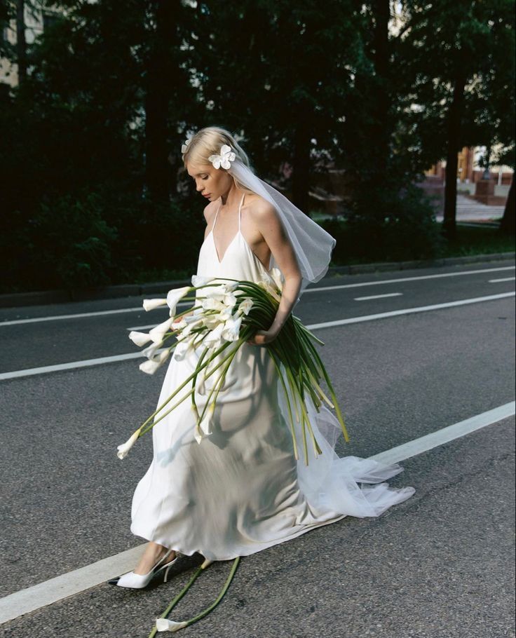 the bride is walking down the street with her bouquet