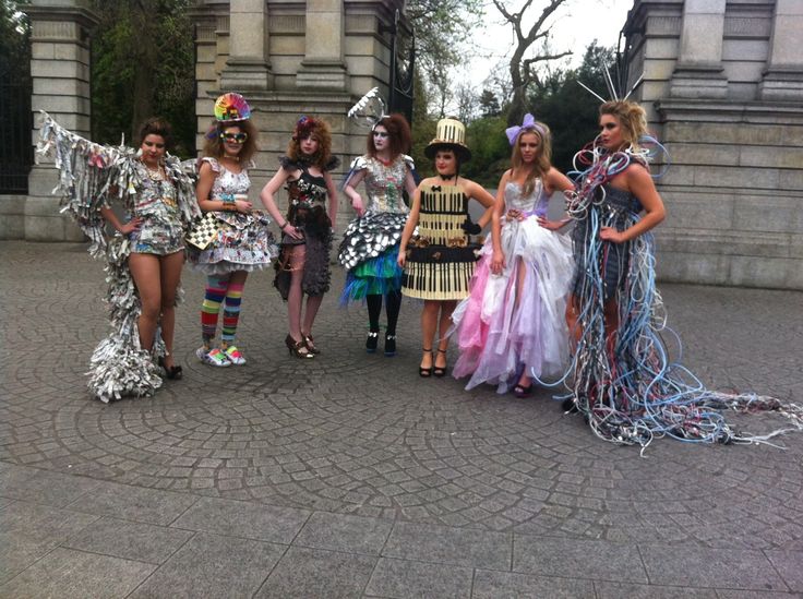 a group of women standing next to each other in front of a stone building wearing costumes