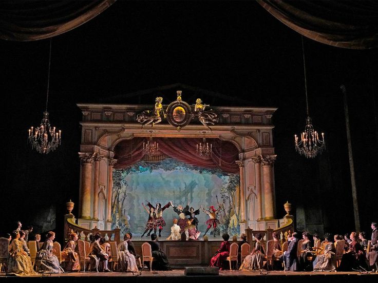 a stage with many people on it and chandeliers