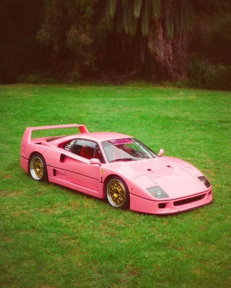 a pink sports car parked in the grass