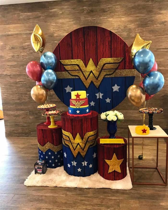 a table with balloons, cake and decorations for a wonder woman birthday party on it