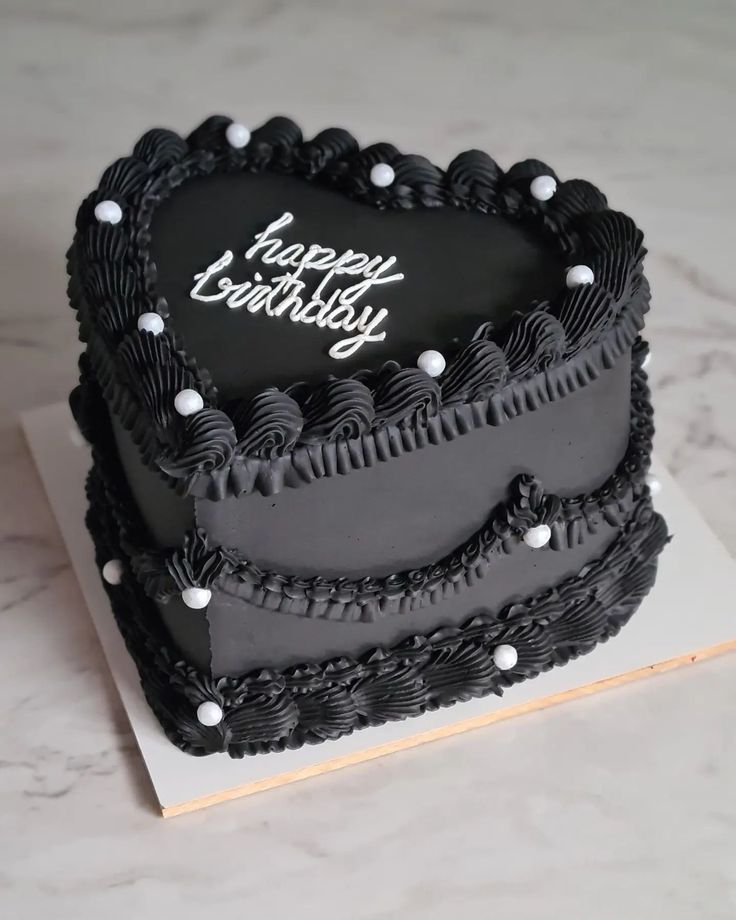 a heart shaped birthday cake with black frosting