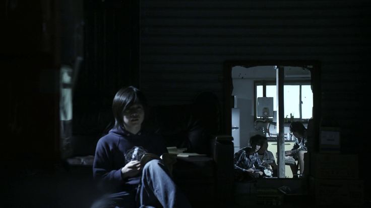 a woman sitting in the dark holding a cell phone